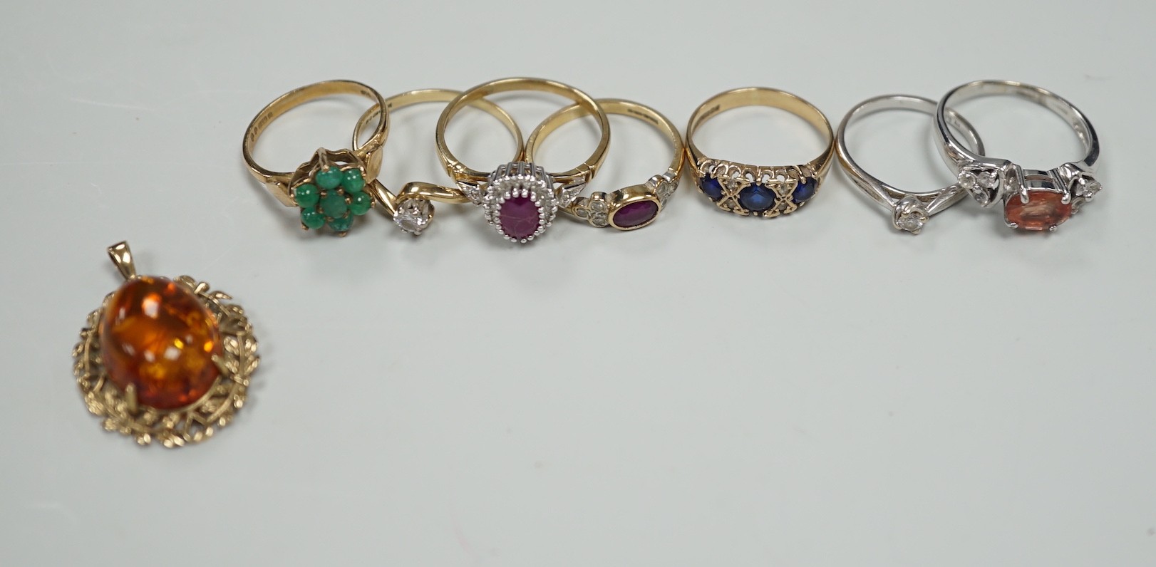 Seven assorted modern 9ct gold and gem set rings, including two solitaire diamond rings, together with a 9ct gold and amber set pendant, gross weight 19.3 grams.